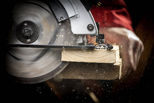 Carpenter with Circular Saw Close-up of carpenter cutting a wooden plank sawhorse stock pictures, royalty-free photos & images