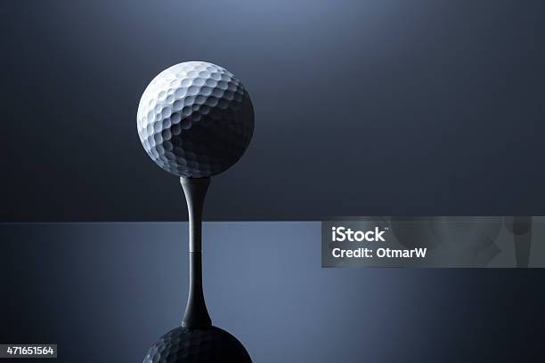 Golf Ball Over Tee Isolated On Dark Blue Reflective Background Stock Photo - Download Image Now