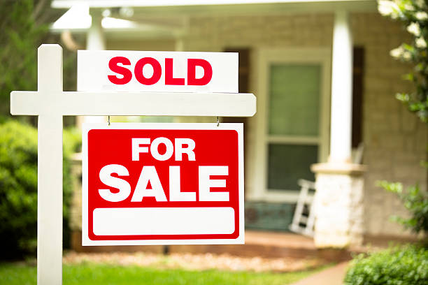 House for sale, sold sign in front yard. No people. Red and white "Sold, Home for Sale" sign in front of a stone, wood house that is for sale and has recently been sold. Green grass and bushes indicate the spring or summer season. Front porch and windows in background. Real estate signs in residential neighborhood. Moving house, relocation concepts. houses for sale stock pictures, royalty-free photos & images