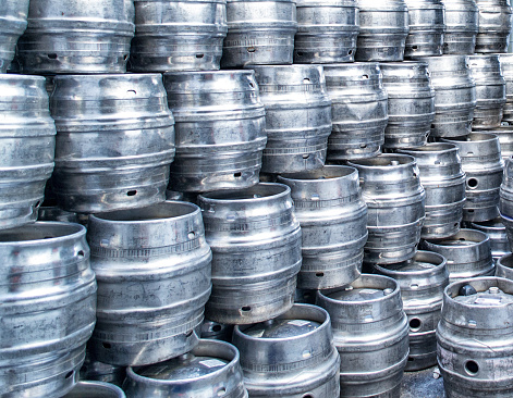 Shiny steel beer barrels stacked high await being filled with real ale
