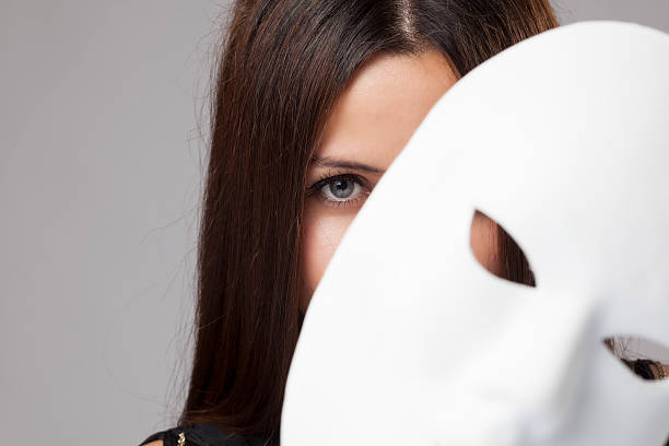 Woman peeking behind mask Woman peeking behind mask,studio shot carnival mask women party stock pictures, royalty-free photos & images
