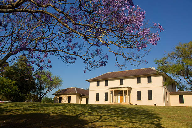 Old Government House at Parramatta, seen beneath blooming jacaranda trees. Australia's oldest public residence, it served as the former home of Governor Macquarie.