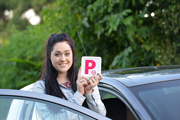 istock Young Australian female teenager learner driver holding a P plate 471665528