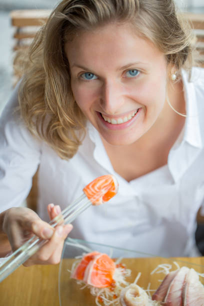istock A woman smiling as she eats sushi 471667376