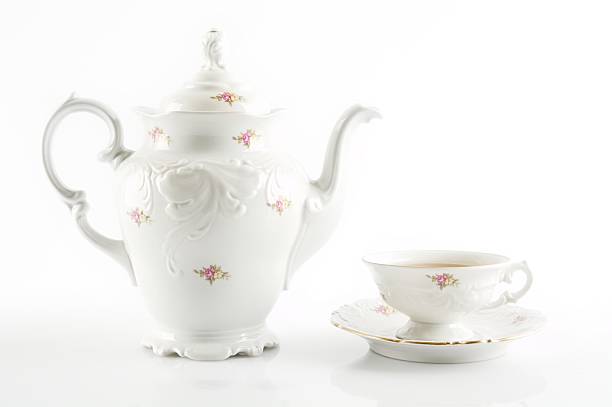 Old-style porcelain jug with tea with a cup of tea on white background retro
