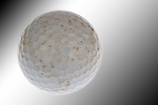Worn and torn golf ball used and dirty and isolated in white