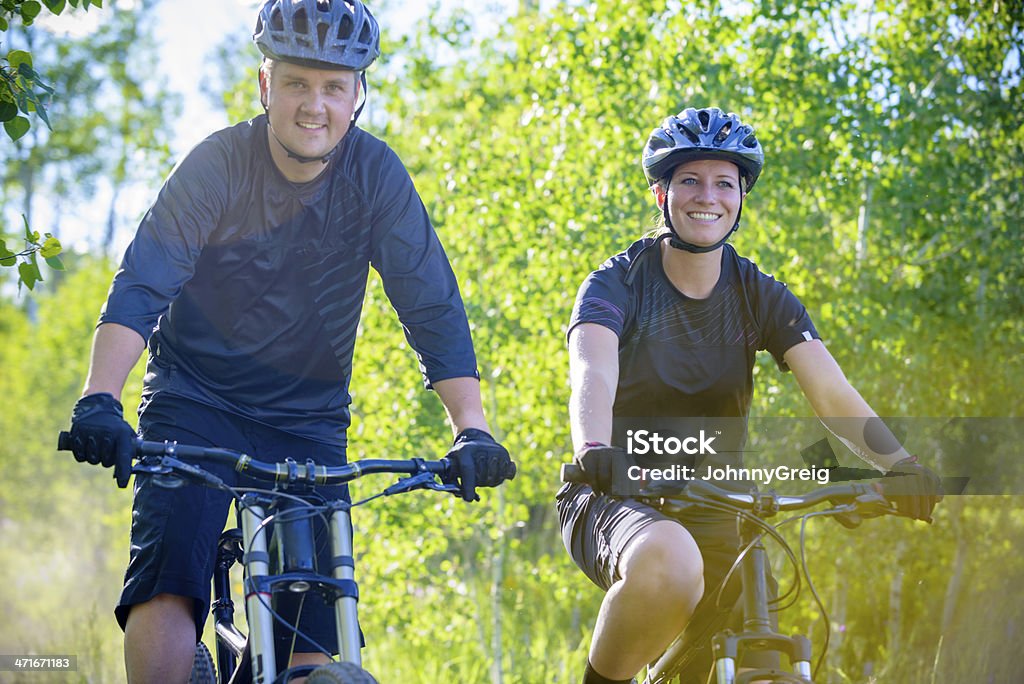 Mountain Biker Couple Happy male and female mountain bikers cycling through an Aspen forest. 20-29 Years Stock Photo