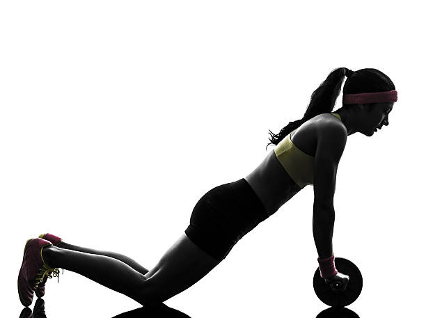 女性のフィットネスワークアウトエクササイズ silhouet 腹筋ローラー - 腹筋ローラー ストックフォトと画像