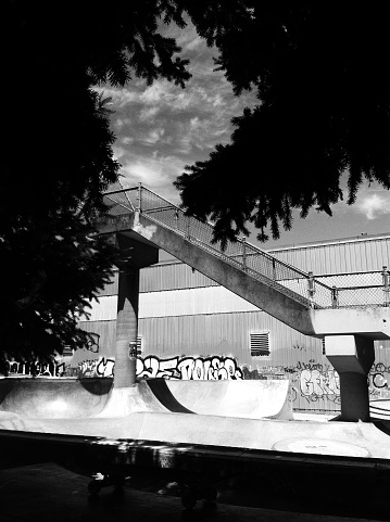 An empty skatepark in SE Portland Oregon with Graffiti and a tall foot bridge that crosses over rail road tracks. Shot on iPhone