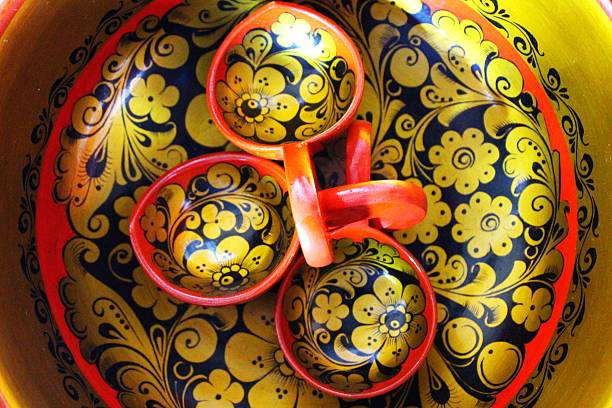 Russian Khokhloma wooden round bowl with three spoons, down view. Khokhloma painting is the Russian wood painting handicraft style and national ornament, known for its vivid flower patterns, red and gold colors over a black background.