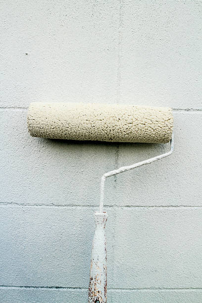 istock White paint roller with blue shaft leaning against wall 471674449