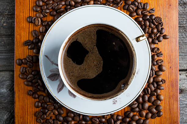 istock Coffee beans and cup of coffee on wooden table 471676394