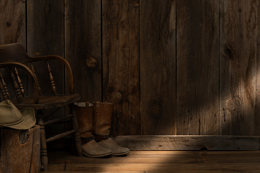 This image shows a subdued Western scene with a streak of sunlight running diagonally through the lower part of the frame. The dark barn wood is suitable for overprinting and the high resolution image is suitable for cropping to a panorama.