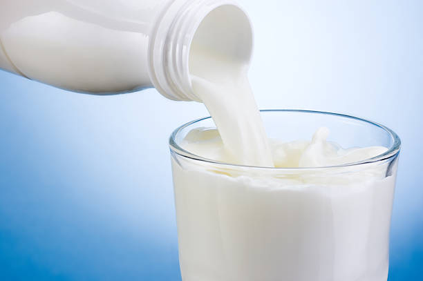istock Pouring milk from plastic bottle into glass on blue background 471679777