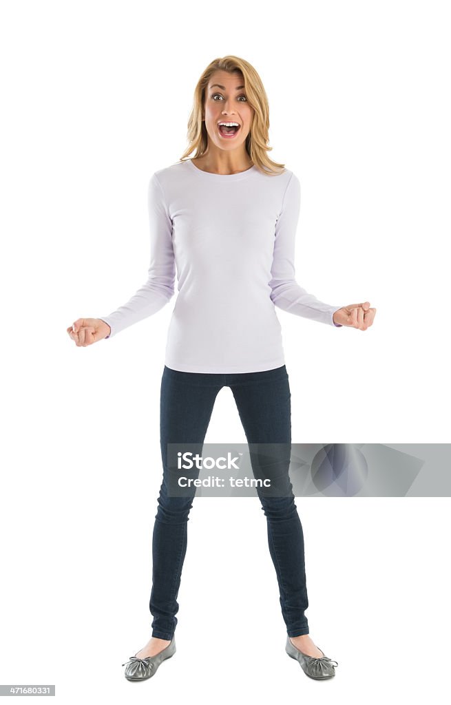 Excited Woman With Clenched Fists Shouting Portrait of excited young woman with clenched fists shouting while standing against white background Women Stock Photo