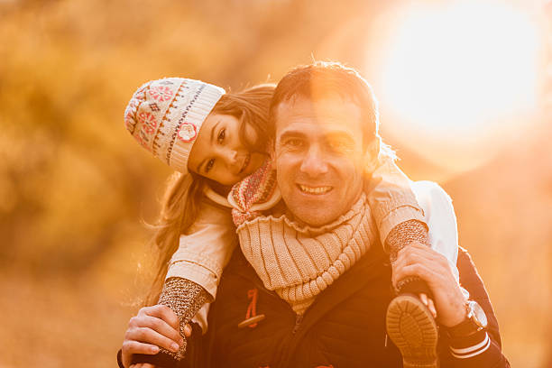 istock Smiling father carrying his daughter on shoulders at sunset. 471680590