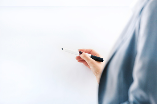 Unrecognizable businessman writing on flipchart, using felt tip pen, copy space