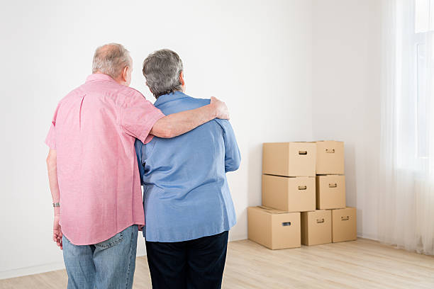 istock Senior couple standing in new empty home with packing boxes 471681824