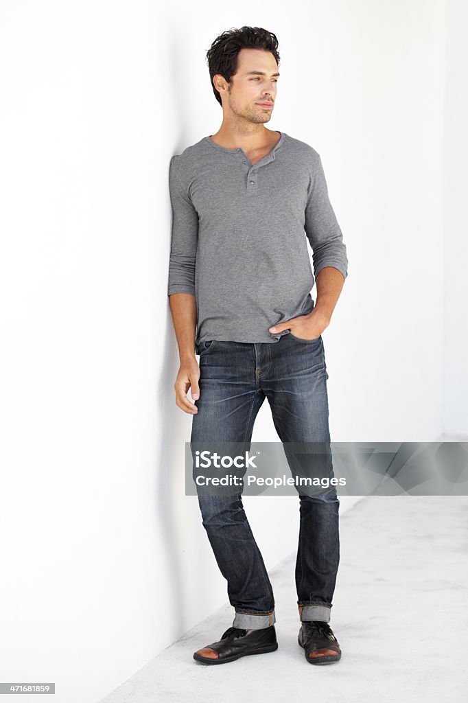 There's no questioning his fashion sense A handsome young man leaning against a wall with his hand in his pocket Leaning Stock Photo