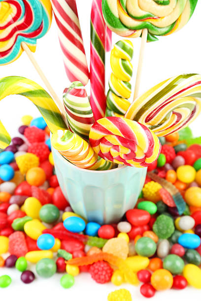 Different fruit candies in cup on white background