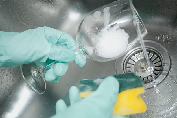 Washing glass Hands covered with gloves washing a wine glass in the kitchen sink, tap running cleaning stove domestic kitchen human hand stock pictures, royalty-free photos & images