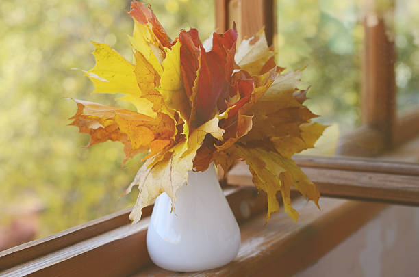 Autumn maple leaves bunch in vase on old wooden windowsill