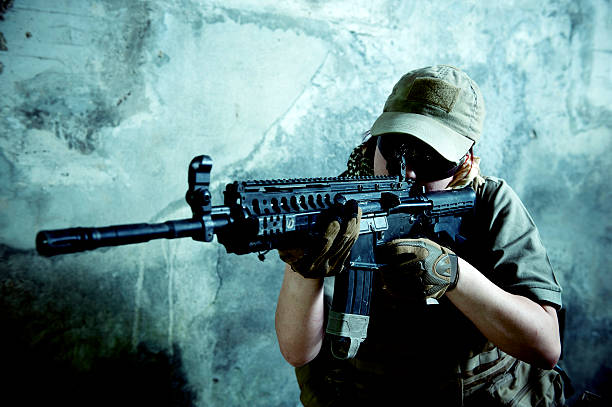 Young Caucasian Woman Soldier Shooting with Automatic Rifle stock photo
