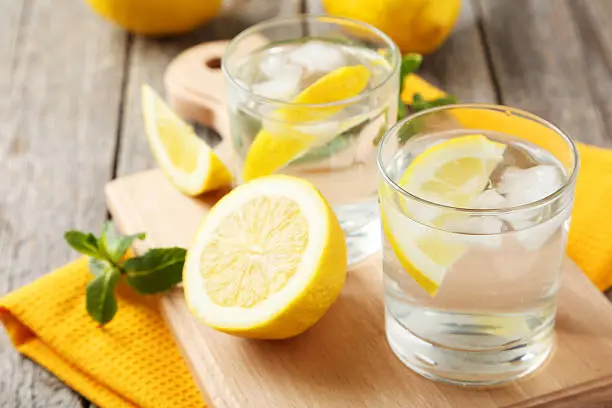 Fresh lemonade with lemon on grey wooden background