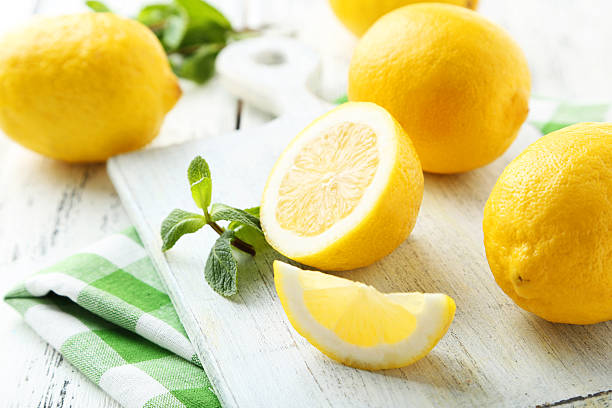 istock Lemons on cutting board on white wooden background 471685344
