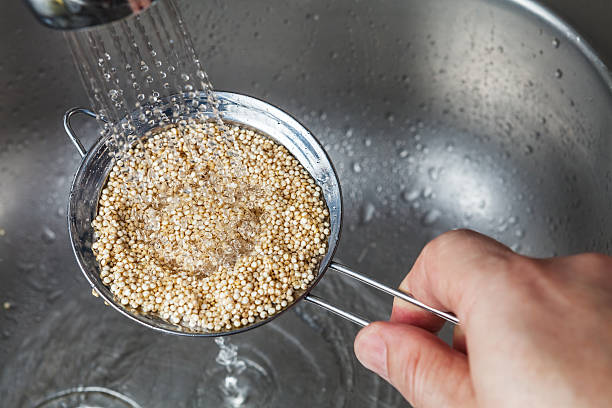 mann hält kleine sieb mit rauer quinoa samen - quinoa stock-fotos und bilder