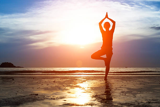 istock Silhouette woman practicing yoga on the beach at sunset. 471687645