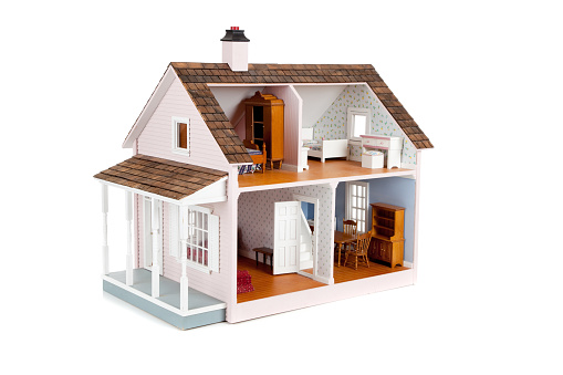 a furnished pink doll house on a white background
