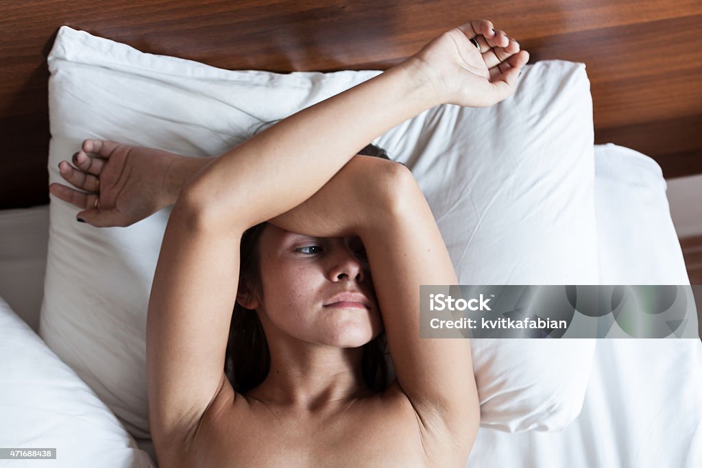 Young naked woman in white bed Young naked woman in white bed in the morning 2015 Stock Photo