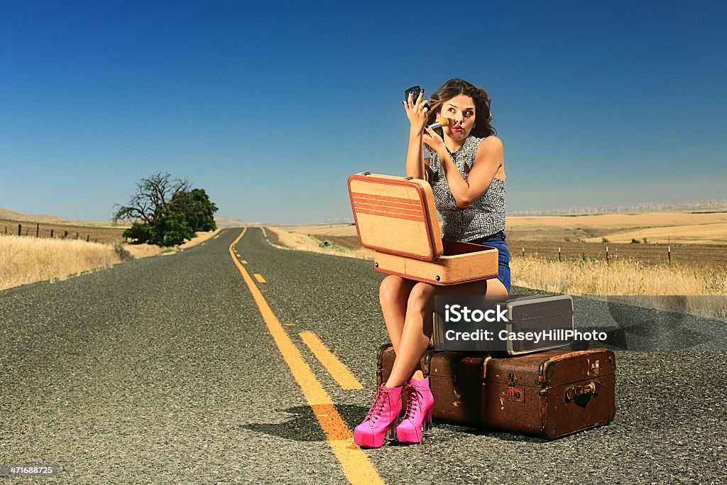 Sexy Brunette Hitch Hiker A beautiful brunette in short shorts needs a ride. She's applying makeup. She has lots of baggage. Any takers? One Woman Only Stock Photo