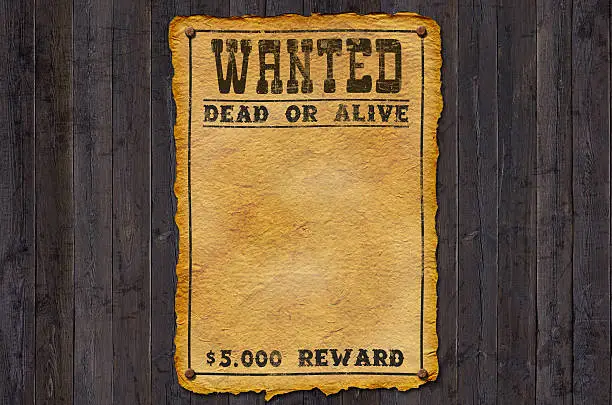 Landscape image with a vertical antique wanted poster in the center.  Poster has burnout edges and yellow textured antique background.  A fine-line border encompasses the poster with dotted corners.  Inside in bold, dark brown, blocky, serif text is the word "WANTED".  This is followed by "DEAD OR ALIVE" in medium text with a fine line directly above and below.  At the bottom, above the border, in medium text are the words "$5,000 REWARD". The remainder of the poster is open.  The poster is layered over a background of weathered gray boards.  The boards are wide and vertical, showing a rough texture and several knots.
