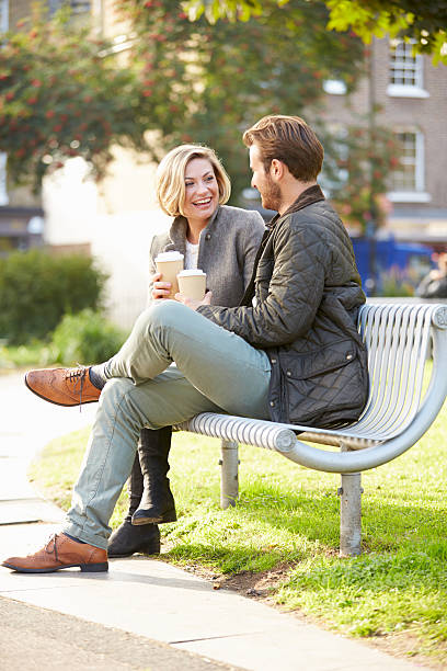 istock Couple Relaxing On Park Bench With Takeaway Coffee 471691724