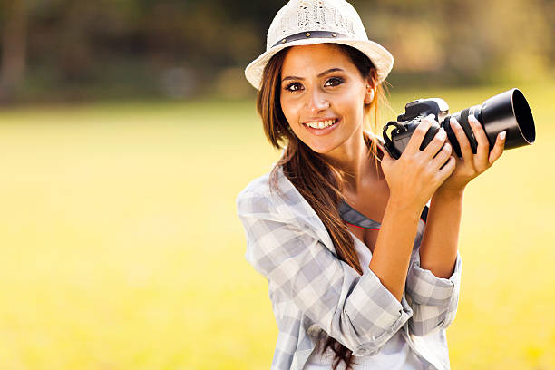 istock attractive young woman holding camera outdoors 471693277