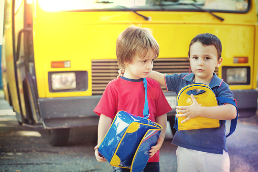3-4 years-old children in front a school bus