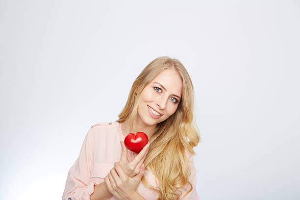 istock young blond woman holding a red heart. isolated on white 471694168