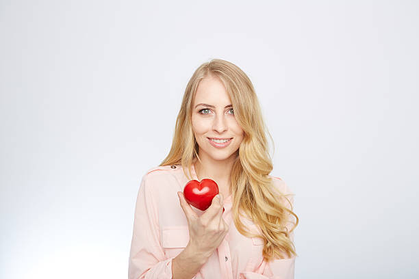 istock young blond woman holding a red heart. isolated on white 471694180