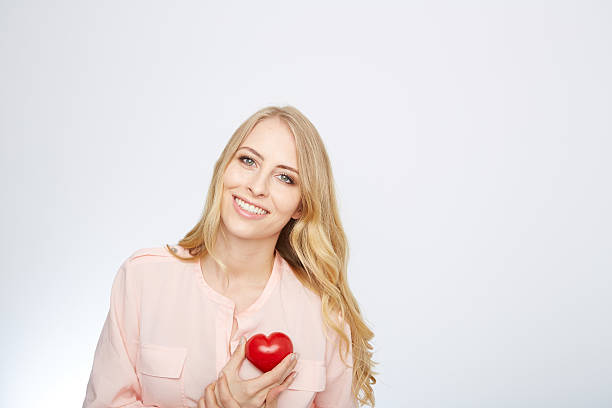 istock young blond woman holding a red heart. isolated on white 471694192
