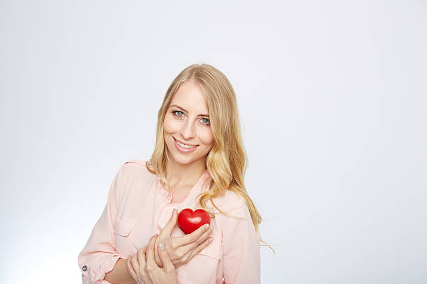 istock young blond woman holding a red heart. isolated on white 471694194