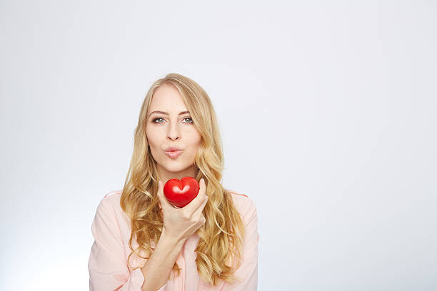 istock young blond woman holding a red heart. isolated on white 471694206