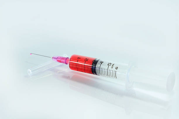 istock syringe filled with red liquid. Isolated on white. 471694469