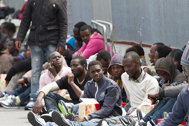 migrants catania harbor Catania, Italy - April 23, 2015: refugees awaiting the bus at Catania Harbor immigrant stock pictures, royalty-free photos & images