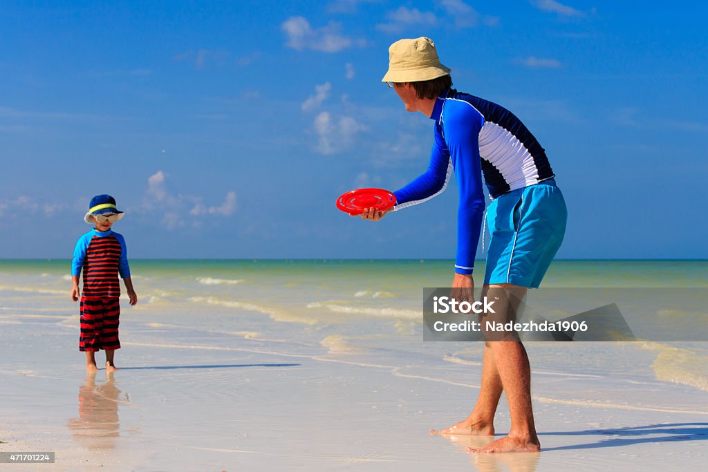 Father and son playing with flying disc at the beach Father and son playing with flying disc at tropical beach 2015 Stock Photo