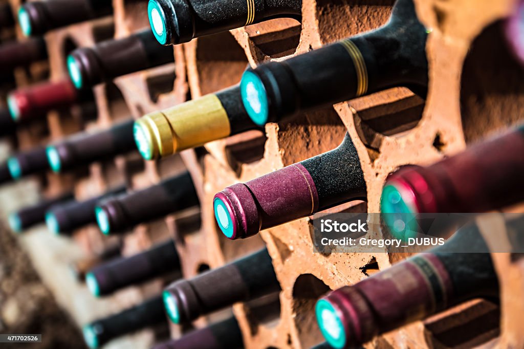 Wine bootles from cellar in selective focus Selective focus of wine rack on wall in brick material full, to store red wine bottle in a row in cellar, cool and in good conditions.Some of those are old wine bottle with dust. Wine Stock Photo