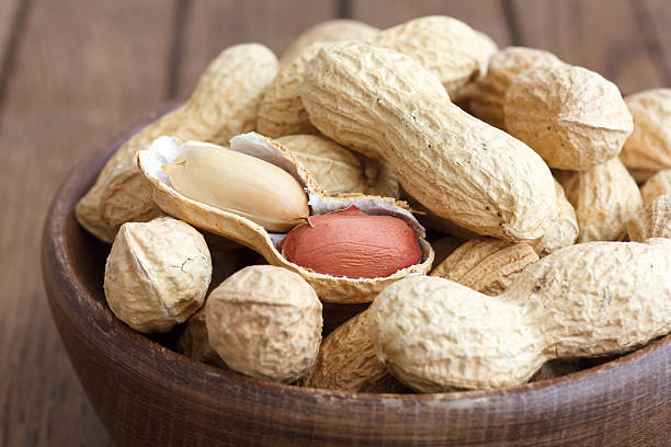 Rustic wood bowl of peanuts in shells.