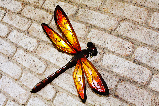 A metal dragonfly attached to a brick wall.