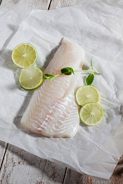 Fish fillet, haddock, limes and herbs on greaseproof paper Fish fillet, haddock, limes and herbs on greaseproof paper haddock stock pictures, royalty-free photos & images